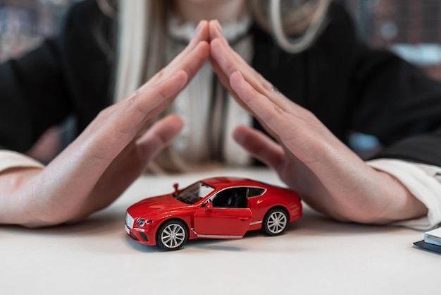 Photo business woman doing insurance on vehicle holding red toy car on desk at office purchase rent or insurance concept