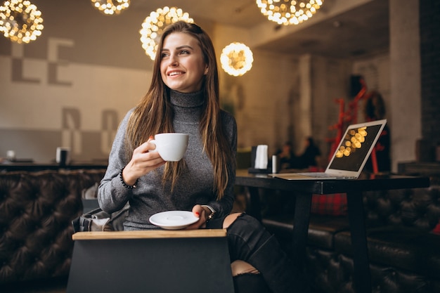 Business woman drinking coffee in a cafe and working on a laptop