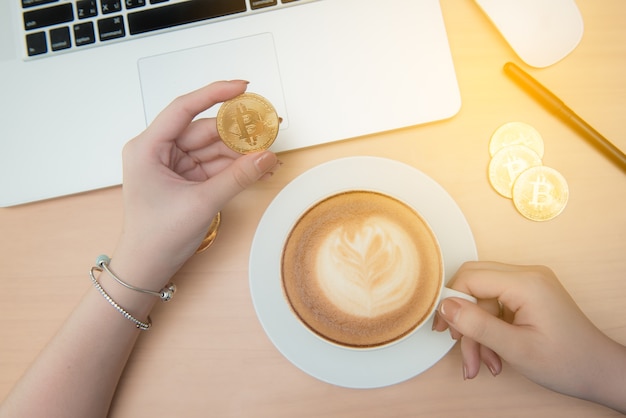 写真 コーヒー/紅茶を飲んでオフィスでラップトップを使用するビジネスウィーク、ビートコイン