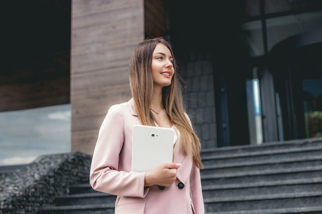 Business woman financial analyst holding the tablet and looking away