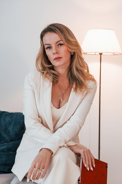 Business woman in formal clothes is indoors posing for the camera