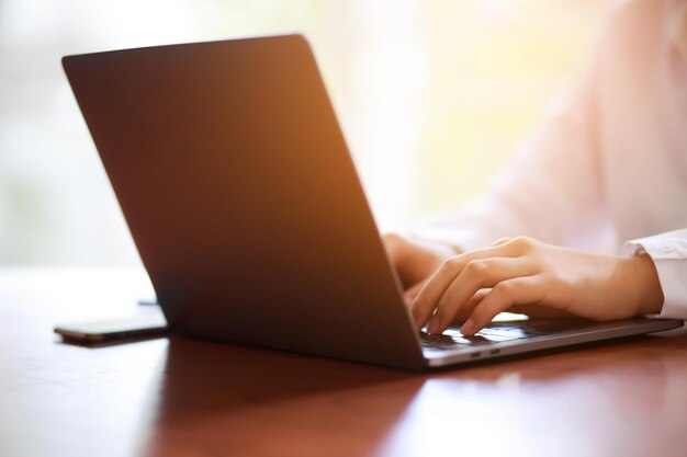 Business woman freelance sitting using working on his computer\
notebook laptop and mobile smart phone send work with coffee cup on\
the table wooden in a cafe coffee shop working women