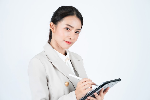 Photo business woman in grey suit using tablet and pen to record the minutes of meeting and work.