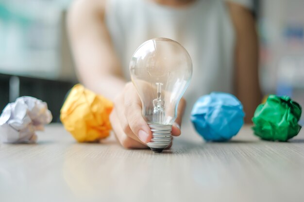 Business woman Hand holding light bulb or lamp with colorful crumpled paper 