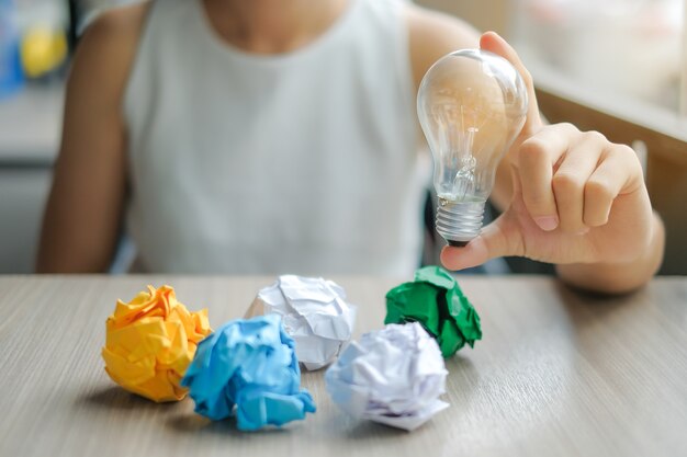 Business woman Hand holding light bulb or lamp with colorful crumpled paper 