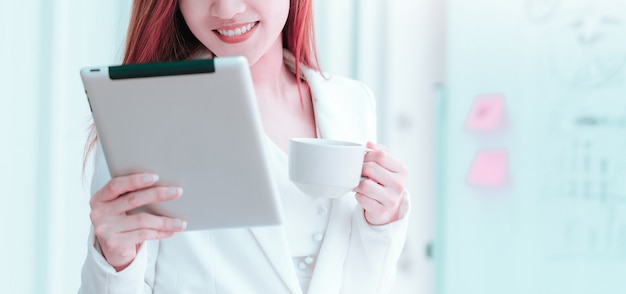 Business woman hand holding a white tablet in office.
