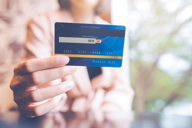 La mano della donna di affari tiene una carta di credito blu.