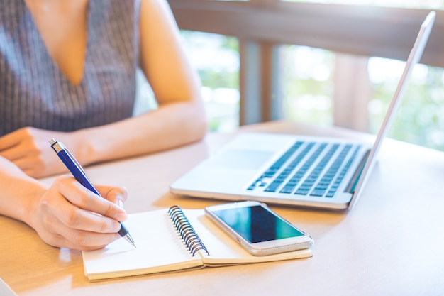 Business woman hand is writing on notepad 