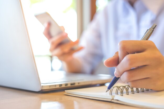 Business woman hand is writing on a notepad