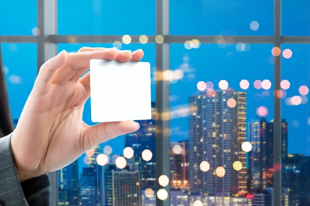 Business woman hand showing white blank card on the office