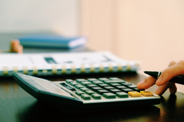 Business woman hand using calculator at office