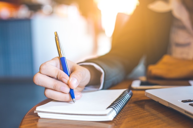 business woman hand  writing on notepad with a pen in office.