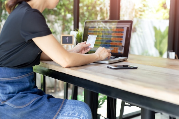 Business woman hands holding credit card doing on line banking with laptop 