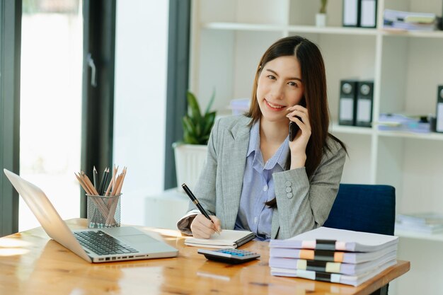 Photo business woman have the joy of talking on the smartphone tablet and laptopon the modern office
