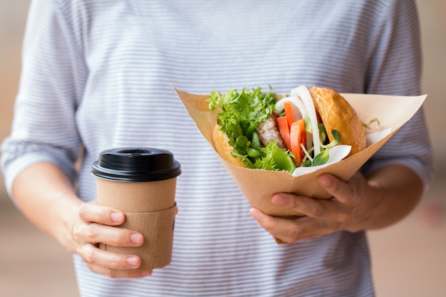 Foto donna di affari pranzando, hamburger con caffè in pausa