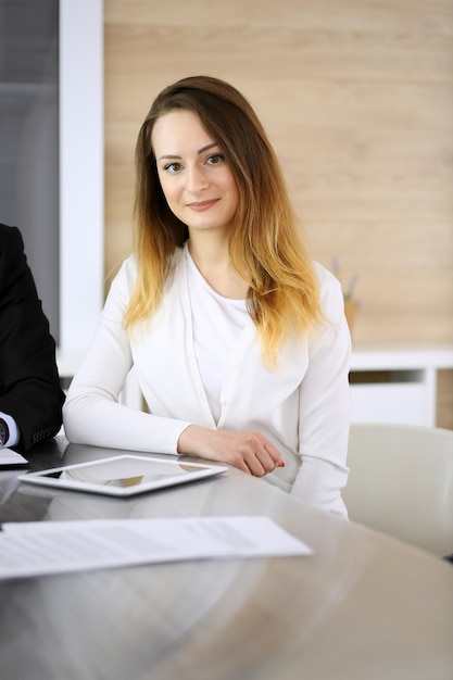 Business woman headshot at meeting in modern office Unknown businesswoman sitting with colleagues at the background Teamwork and partnership concept