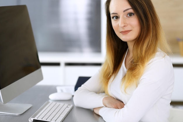 Foto colpo di testa della donna d'affari sul posto di lavoro in un ufficio moderno imprenditrice sconosciuta seduta dietro il monitor del computer giovane ragioniere o segretario sembra buono