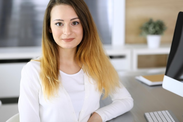 Foto colpo di testa della donna d'affari sul posto di lavoro in un ufficio moderno imprenditrice sconosciuta seduta dietro il monitor del computer giovane ragioniere o segretario sembra buono