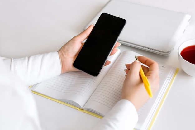 A business woman at her desk with a mobile phone and a pen in her hands