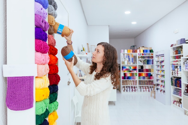 Business woman at her own retail shop picking up wool yarns