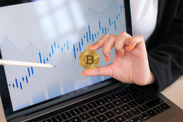 Photo business woman hold bitcoin actual coin in hand background with computer laptop