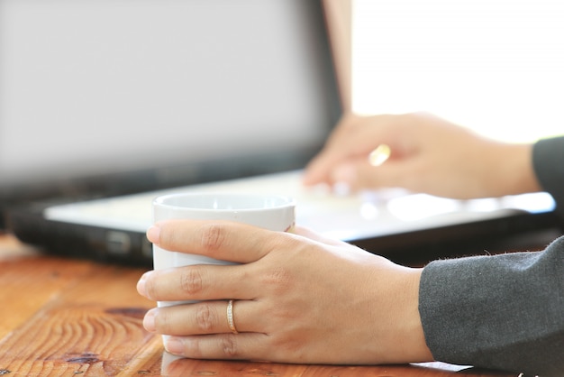 Business woman hold a coffee cup and using laptop computer