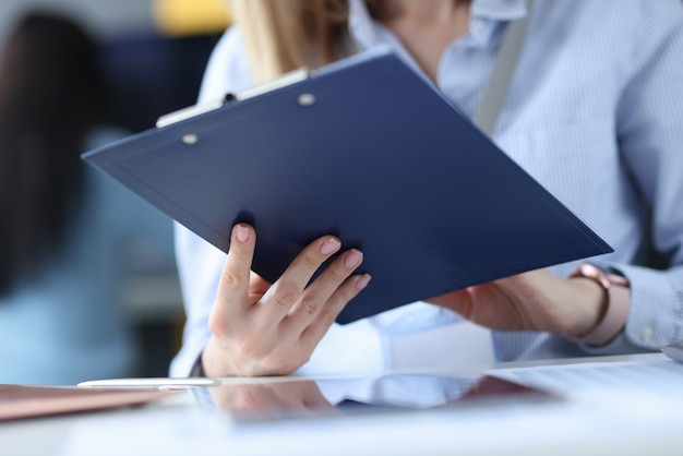 Business woman holding clipboard with documents in her hands at workplace