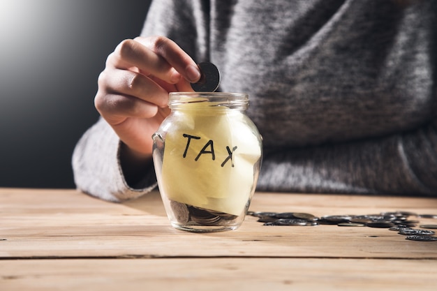 Business woman holding coins with tax jar