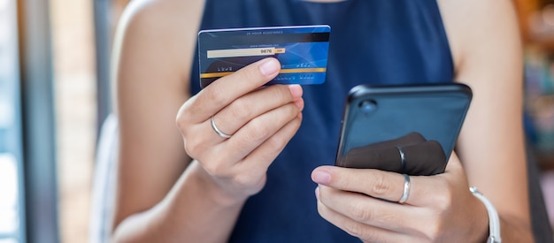 Carta di credito della tenuta della donna di affari e smartphone usando