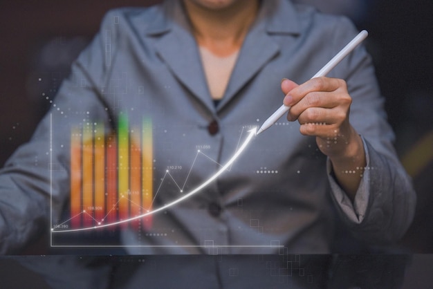 Business woman holding digital pencil and touching on top of up trend arrow stock chart and trading market