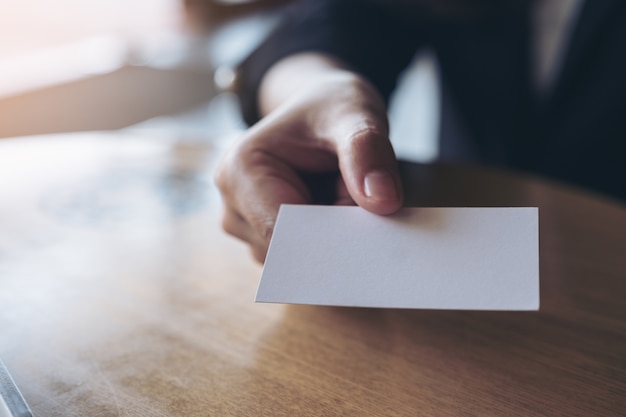 Business woman holding and giving  an empty business card to someone on table in office