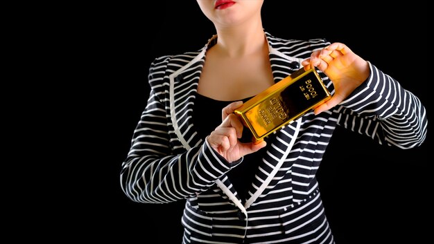Business woman holding the gold bar on black background