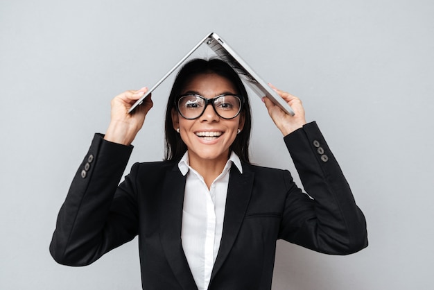 Business woman holding laptop on head