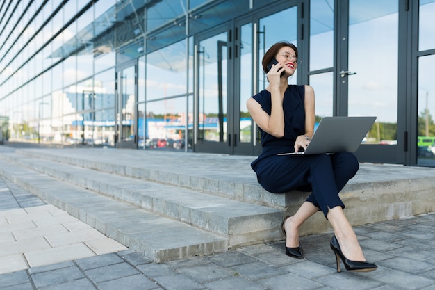 Бизнес женщина, держащая ноутбук на открытом воздухе