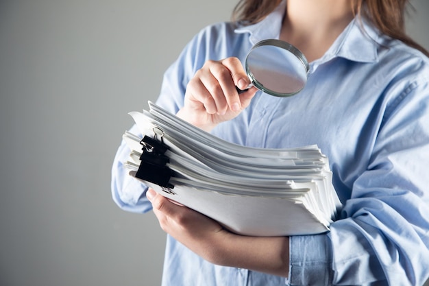 Business woman holding magnifying glass and documents