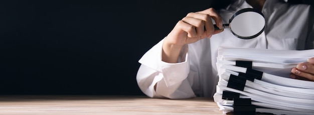 Business woman holding magnifying glass and documents