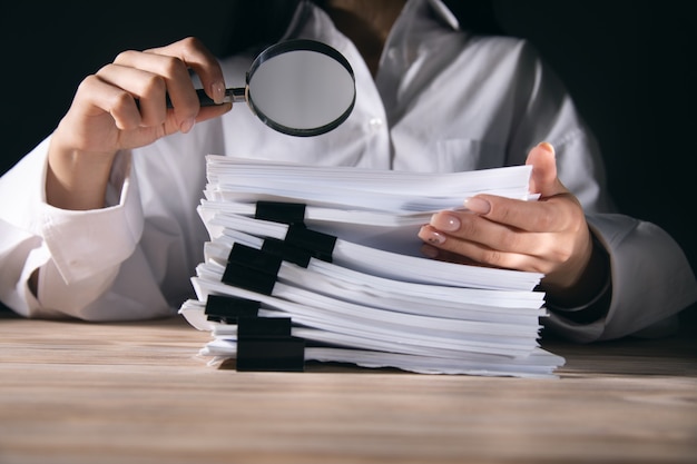 Business woman holding magnifying glass and documents