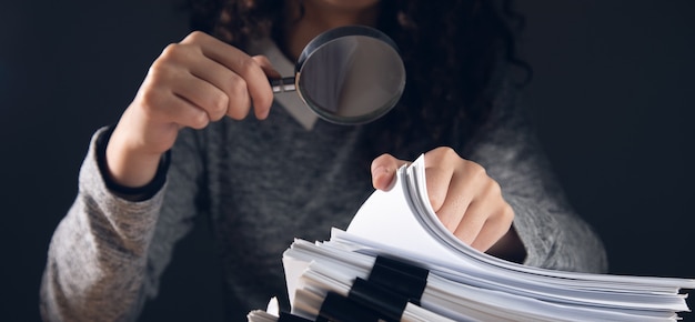 Business woman holding magnifying glass and documents