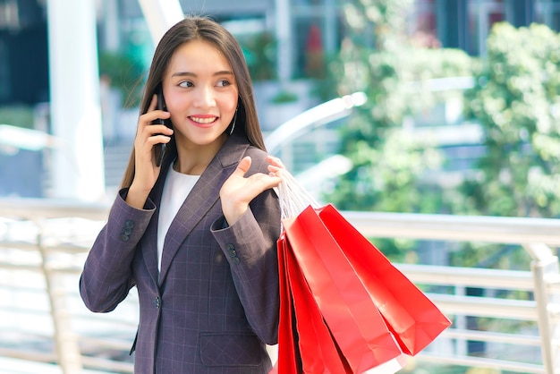 Business woman holding smartphone and shopping bags