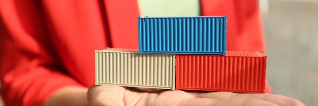 A business woman holds in the palm of the cubes of containers a closeup cargo transportation