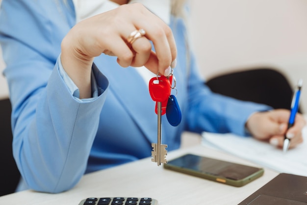 A business woman is sitting in an office and holding keys in her hand