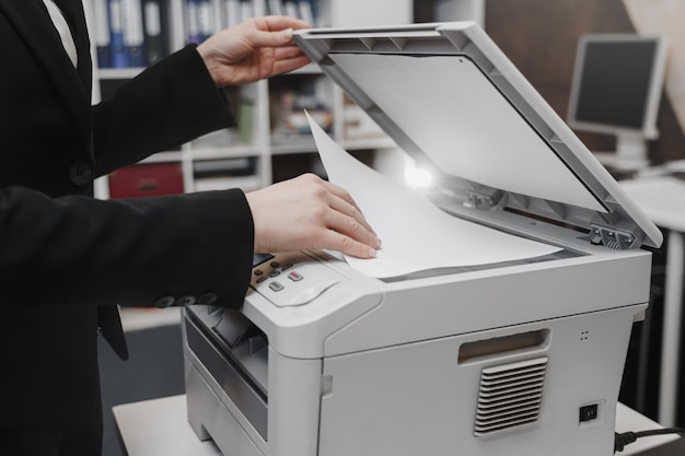 La donna d'affari sta utilizzando la stampante per la scansione e la stampa di documenti