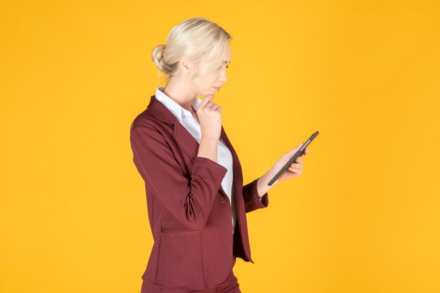 Business woman is using tablet  in studio yellow background 