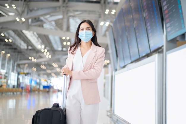 Una donna d'affari indossa una maschera protettiva all'aeroporto internazionale, viaggia sotto la pandemia covid-19,