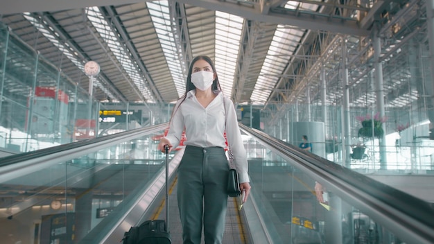 A business woman is wearing protective mask in International airport, travel under Covid-19 pandemic