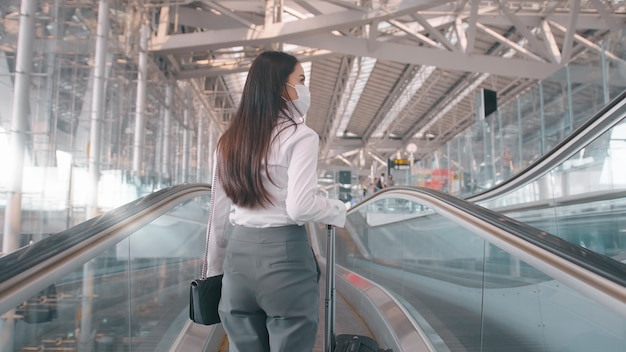 A business woman is wearing protective mask in International airport, travels under Covid-19 pandemic