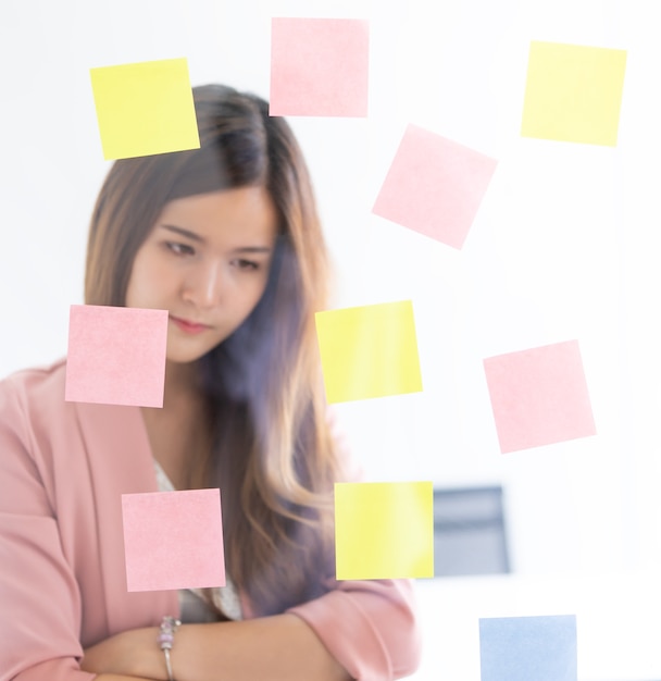 Photo business woman is writing idea on to post it windows for plan