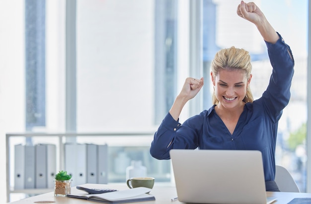 Business woman laptop and celebration for winning promotion or victory bonus at office desk Happy female employee celebrating win deal or discount on sales or good news on computer at workplace