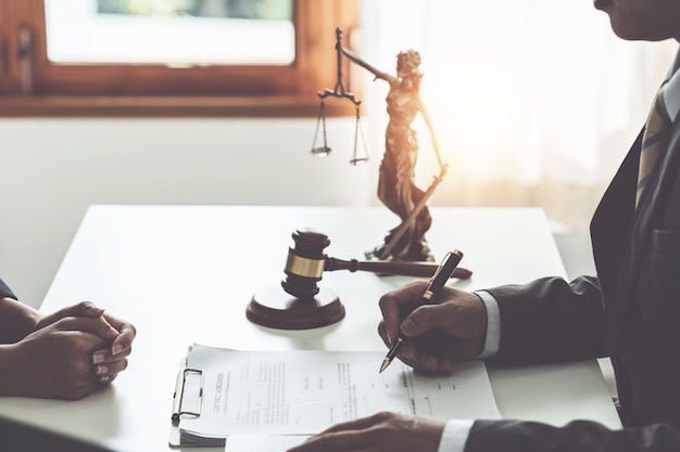 Business woman and lawyers discussing contract papers with
brass scale on wooden desk in office law legal services advice
justice concept