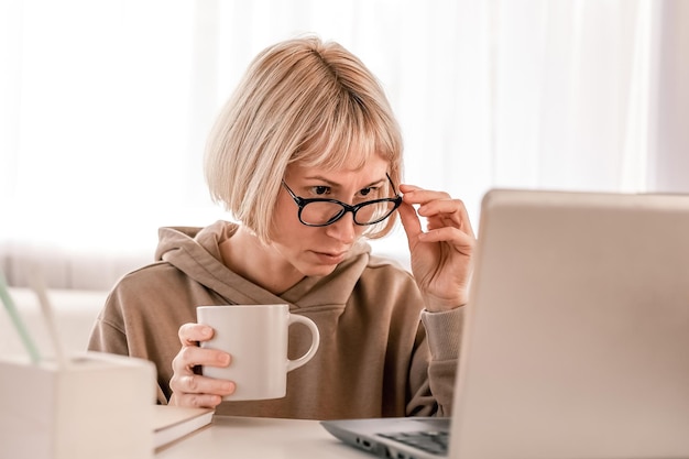 Business Woman listening educational lecture on computer watching webinar studying on online courses writing notes in paper copybook elearning concept